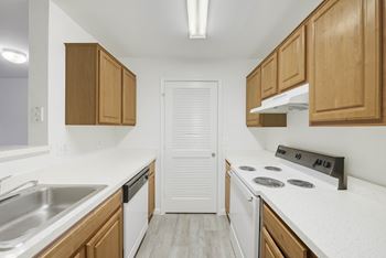 Galley kitchen with wood cabinets and white appliances